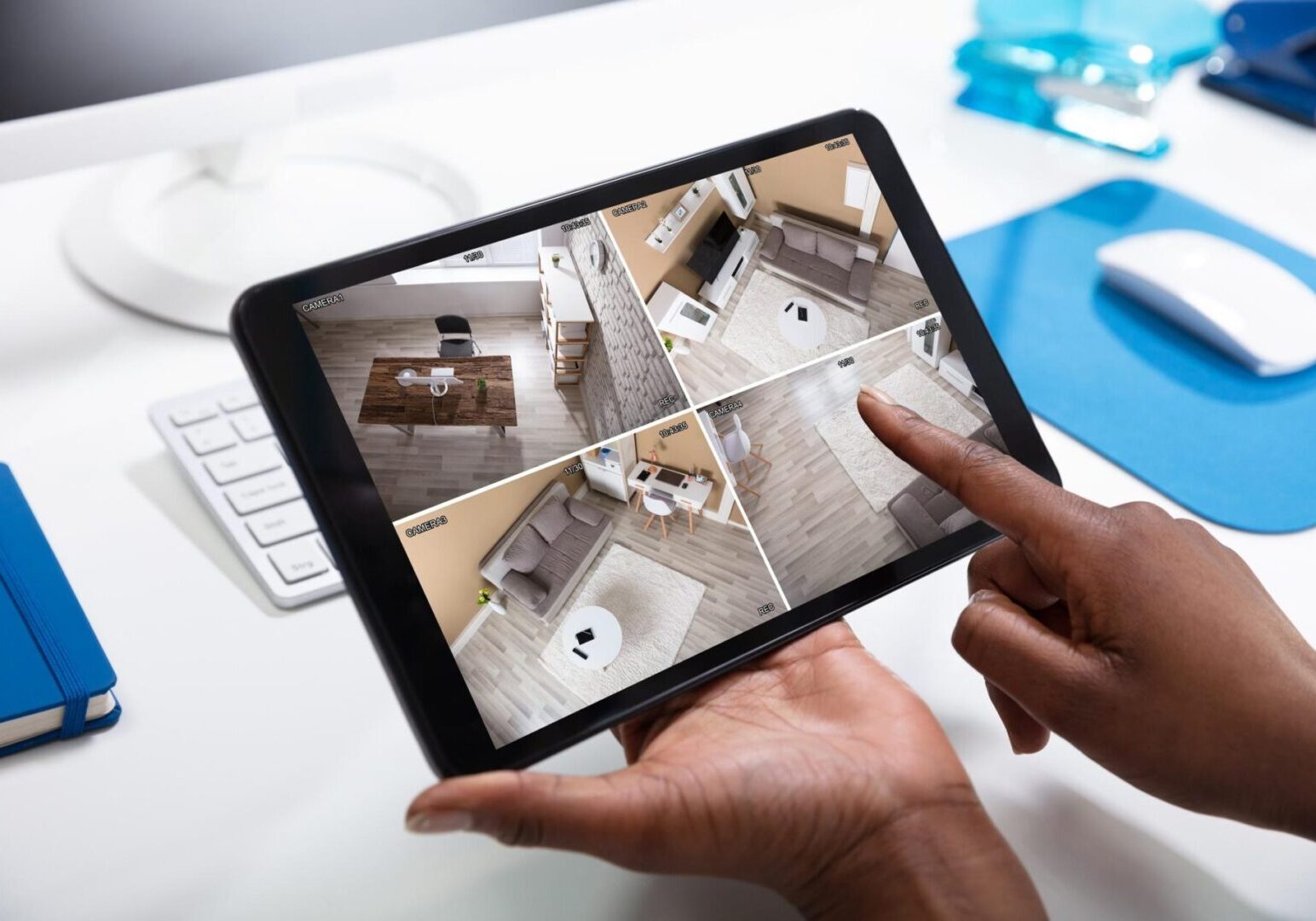 Here's an alt tag for the image: Hands viewing multi-camera security footage.