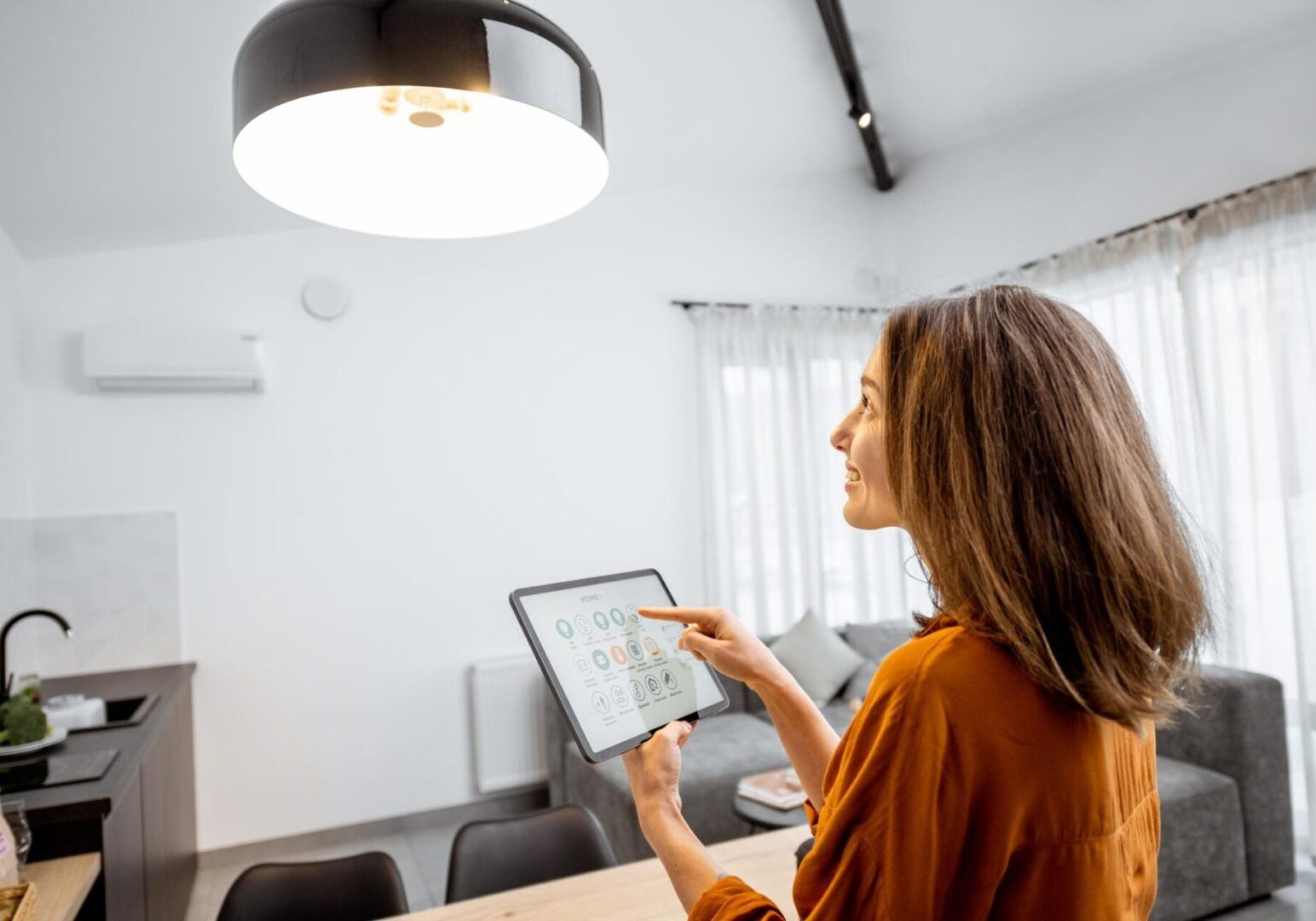 Woman uses tablet to control smart home.